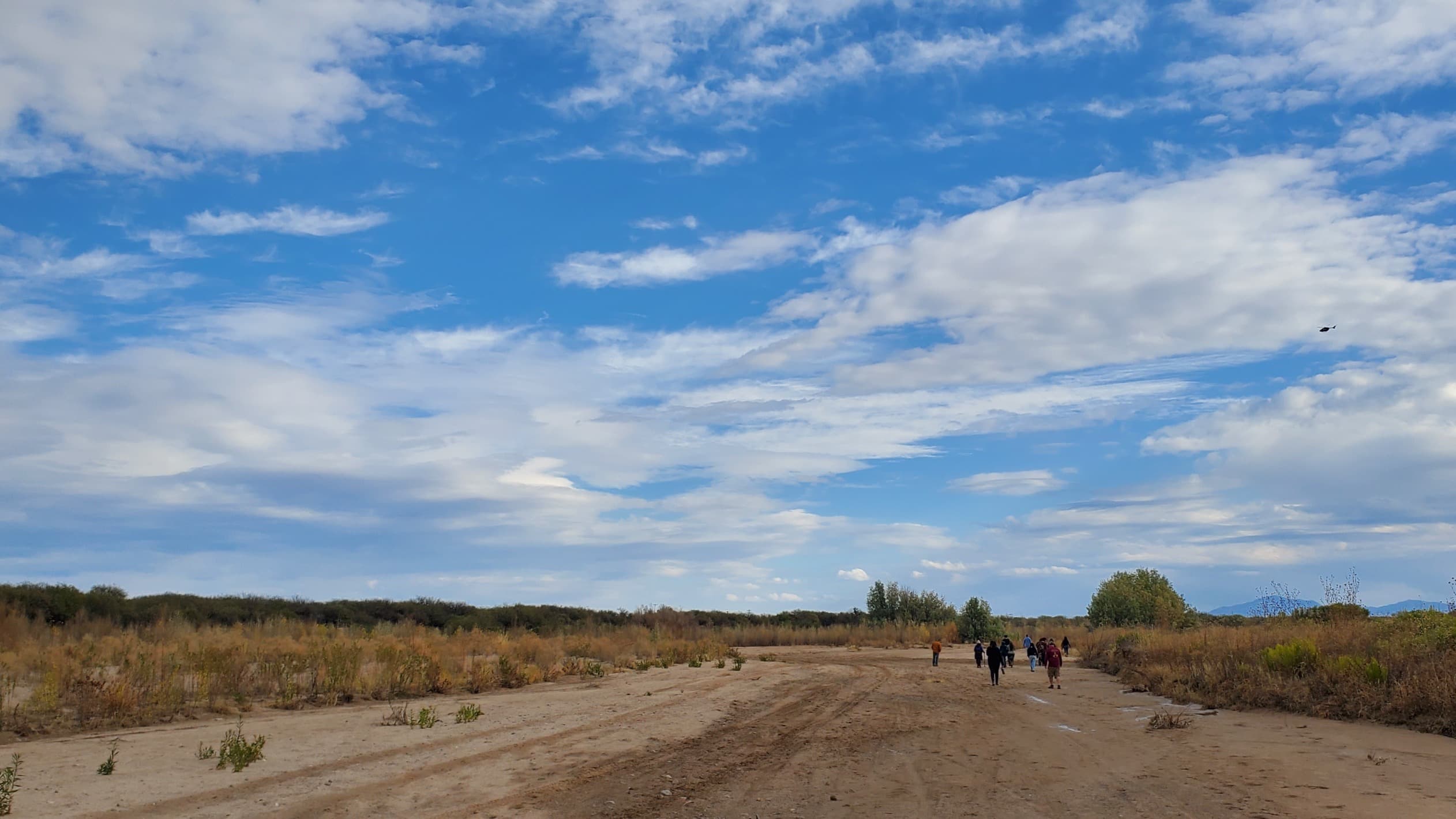 Community members walking a desert path toward water